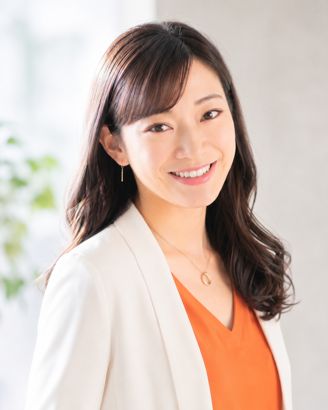 講師の写真。白いジャケットとオレンジの服を着て微笑む姿